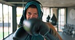 Headphones, gym and man doing a boxing exercise to practice for a competitive fighting match. Fitness, sports and athlete doing a MMA workout training for competition while listening to music in gym.