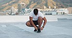 Fitness, sports shoes and athlete in the city preparing for a workout on a rooftop in Mexico. Wellness, health and man tying the laces of his sneakers before a exercise or training in a urban town.