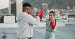 Fitness, personal trainer and woman boxing on a rooftop of a city building training in a cardio workout exercise. Smile, couple and happy fighting sports coach teaching a female boxer safety outdoors