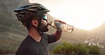 Fitness, break and male cyclist drinking water while cycling in nature. Exercise, workout and endurance with man drink from bottle for hydration during competitive cardio tranining for stamina 