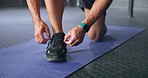 Fitness, man and shoe lace for sport training, workout or exercise on a mat at the gym indoors. Active male hands tying shoes for sports run, cardio or motivation in sportswear for healthy exercising