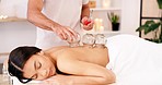 Woman, spa and cupping therapy on patient back, therapist putting cups on skin for pain, blood flow and health benefits. Female relax on bed for deep tissue massage with traditional medicine