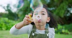 Black girl kid blowing soap bubbles in park, garden and nature, having fun, joy and childhood development, freedom and relax in sunshine. Excited child playing with bubble wand for outdoor toy games