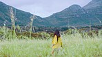 Countryside, freedom and woman jumping in field for travel, adventure and nature walk in India. Earth, summer and holiday fun of Indian girl in green meadow with mountain and happy smile.

