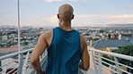 Black man, runner and fitness, running through urban city for exercise and cardio while listening to music or podcast with earphones outdoor. Workout motivation, back view of athlete and run in city.