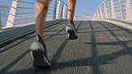 Fitness, city and legs running on a bridge in a cardio workout or exercise with speed training for a marathon in New York. Footwear, runner or shoes of sports athlete sprinting on asphalt in summer