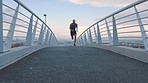 Sports, man and fitness on a bridge in a city, intense, cardio and sprint at sunrise against sky background. Training, exercise and guy runner exercise downtown for marathon, practice and endurance 