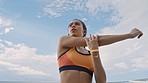 Fitness, music and stretching with a sports woman outdoor on a blue sky background for cardio or endurance. Motivation, heath and wellness with a female athlete doing a warm up before a workout