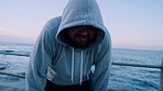 Tired, fitness and beach running of a man with sport fatigue from marathon training outdoor. Plus size, runner and athlete breathing from run exercise by the ocean and sea at sunset after sports