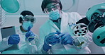 Two scientists using syringe while modifying and mixing chemicals in a medical research lab from below. Chemists create a cure for a virus. Lab workers experimenting and recording their findings