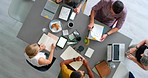 Meeting, planning and collaboration with a team sitting around a table from above with technology. Laptop, documents and diversity with a business woman writing in an office with man colleagues