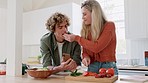 Couple, phone and cooking while tasting food in home kitchen. Love, care and woman cutting vegetables and feeding man, bonding and looking at recipes on mobile while making a delicious meal in house.