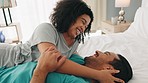 Couple, love and bed for bonding, talking and happiness in morning while having conversation to wake up and be happy together at home. Interracial man and woman in their apartment or hotel room