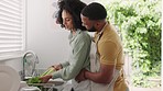 Couple, cooking and cleaning vegetables, healthy food and celery in kitchen for lunch, meal and dinner with love, care and happiness together. Hungry black man hug happy woman and prepare vegan diet