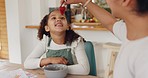 Mother, child and strawberry feeding in house or home kitchen for breakfast, healthy food or snack with bonding parent. Smile, happy and talking girl eating fruit with mom in morning wellness routine