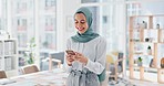 Phone, social media and good news with a business muslim woman reading a text message while working in her office. Mobile, contact and smile with a happy islamic female employee typing or texting