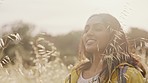 Indian woman, wheat plants and calm person in nature feeling peace from holiday and freedom. Female on summer travel adventure hiking in a farm field or countryside with a smile and lens flare