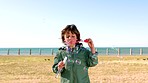 Child, bubbles and beach park with kid outdoor while on vacation at sea for fun, freedom and travel with happiness and wonder. Boy blowing soap bubble wand on grass field to relax in peace and calm