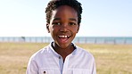Happy, smile and face of child at beach park for summer break, vacation and youth. Freedom, health and happiness with portrait of young boy laughing by seaside for peace, lifestyle and holiday
