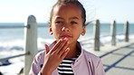Child, childhood and portrait blowing kiss by the sea on a promenade during a summer vacation. Little girl, kissing and having fun during a getaway or holiday in Sea Point, South Africa 