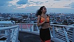 Runner, black woman and bridge in city with music streaming earphones at night in Cape Town, South Africa. Wellness, exercise and running girl with audio playlist app for fitness, training and focus.