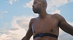 Tired, sweat and fitness with a sports black man tired after a cardio workout for fitness outdoor. Cardio, exhausted and sweating with a male athlete or resting after exercise in nature with blue sky