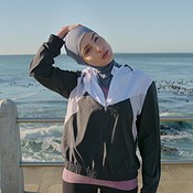 Sporty woman with a hijab warming up by doing stretch exercises outdoors in  the morning. Athletic