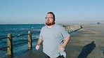 Workout, running and sea exercise of man with obesity doing cardio outdoor for wellness. Fat, training and beach road run of an athlete doing sports fitness and runner sport for marathon by the ocean