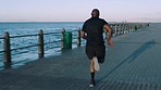 Black man, runner by the beach and running for sports fitness, cardio body exercise and training for a marathon competition. Athlete on outdoors run, healthy sport by sea and a cardiovascular workout