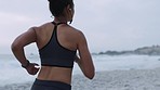 Beach running, woman and headphones of a runner by the ocean doing exercise with music. Back view of marathon training, sports and fitness workout by the Florida sea for wellness in nature with audio