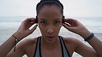 Woman runner, beach and face with headphones, music and focus in closeup for training, exercise and fitness. Black woman, streaming online and internet radio for motivation, wellness and sea running