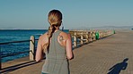 Running, woman and fitness by the beach, exercise and runner outdoor for cardio with earphones for music and sports motivation. Workout, training for marathon and wellness with healthy active life.