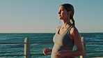 Running, pregnant and fitness with a woman athlete on the promenade by the sea or ocean for exercise. Wellness, health and pregnancy with a female runner listening to music while training outdoor