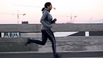 Fitness, woman and running in the city for exercise, cardio workout or training in the outdoors. Active athletic female runner in sports exercising on a run in the street of a urban town for wellness