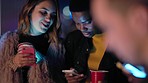 Woman, friends and phone at night in social media, networking or communication in the outdoors. Women in discussion, conversation or talking browsing on smartphone together in the evening at party
