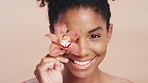 Beauty, happy and face of black woman with flower for organic skincare routine, natural cosmetics and self care. Makeup, spa salon and African model portrait with floral product on studio background