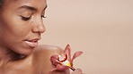 Black woman, face or skin glow and flowers on pink studio background in organic dermatology, vegan skincare routine or natural wellness. Zoom, beauty model or orchid plants in facial makeup cosmetics