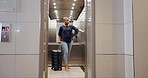 Suitcase, travel and black woman in elevator in hotel on vacation, holiday or trip. Luggage, technology and female tourist walking into a lift at resort, motel or lodge and pressing button to go down