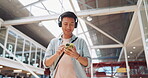 Phone, music headphones and Asian man walking in mall streaming podcast or radio. Technology, travel and happy male listening to song, audio sound or playlist on mobile smartphone in urban building.