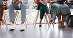 Interview, hiring and legs of business people waiting in a line in the lobby at a modern office. Recruitment, human resources and corporate candidates sitting in a row for a meeting in the workplace.