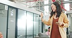 Office, greet and woman on her phone walking to her desk while talking to her colleagues or friends. Happy, smile and Asian female creative employee greeting or waving to her coworkers in workplace.