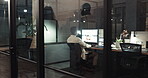 Computer, night and overtime with a business black man at work behind glass in an office on a deadline. Dark, target and desktop with an african male employee working on a project at his desk