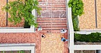 Overhead, business people and walking outdoor on brick paving of building or campus with men and women. Employees, staff or diverse group on stairs leaving or to start work or break at workplace