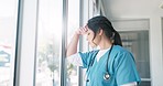Doctor, woman and window with headache, stress and anxiety in hospital workplace with hand on head. Young medic, mental health problem and sad in clinic with bad news, depressed and burnout at job
