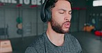 Headphones, kettlebell and man training in gym for fitness, health and wellness. Sports music, energy and face of male athlete streaming podcast or radio for motivation, exercise and weight workout.