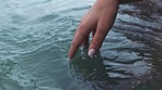 Manicure hand of woman touch water in sea, river or lake with calm waves in nature for peace, relax and freedom. Girl or female person touching ocean liquid on tropical beach holiday vacation trip