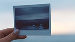 Hands, nature and photograph of a sea in the hand of a woman on the beach by the ocean at sunset with a view of the horizon and sky in the background. Travel, earth and polaroid with a female outside