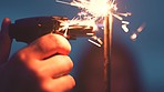 Hand of person lighting a sparkler, fireworks or firecracker for celebration with a blurred background. Glow, burn or bonfire night party, flame or fire, sparks or light to celebrate at new year rave