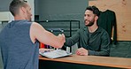 Handshake, discussion and men with a gym membership, welcome and signing paperwork for training. Networking, deal and man writing on a contract from a personal trainer and shaking hands fitness