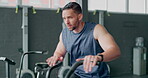 Exercise bike, fitness and sweat with a man athlete in a gym for a cardiovascular workout. Elliptical machine, exercise and breathing with a male cycling to increase health, cardio or endurance